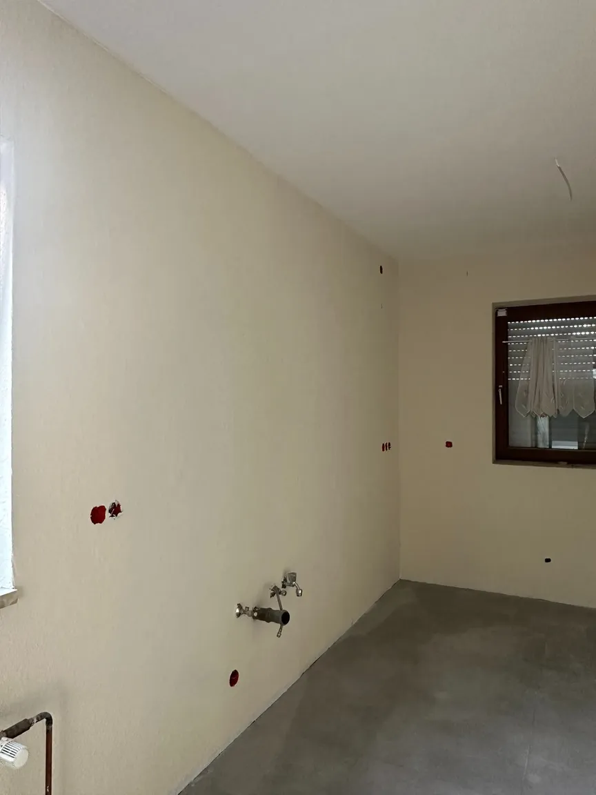Hell gestrichene Küchenwand mit vorhandenen Wasseranschlüssen