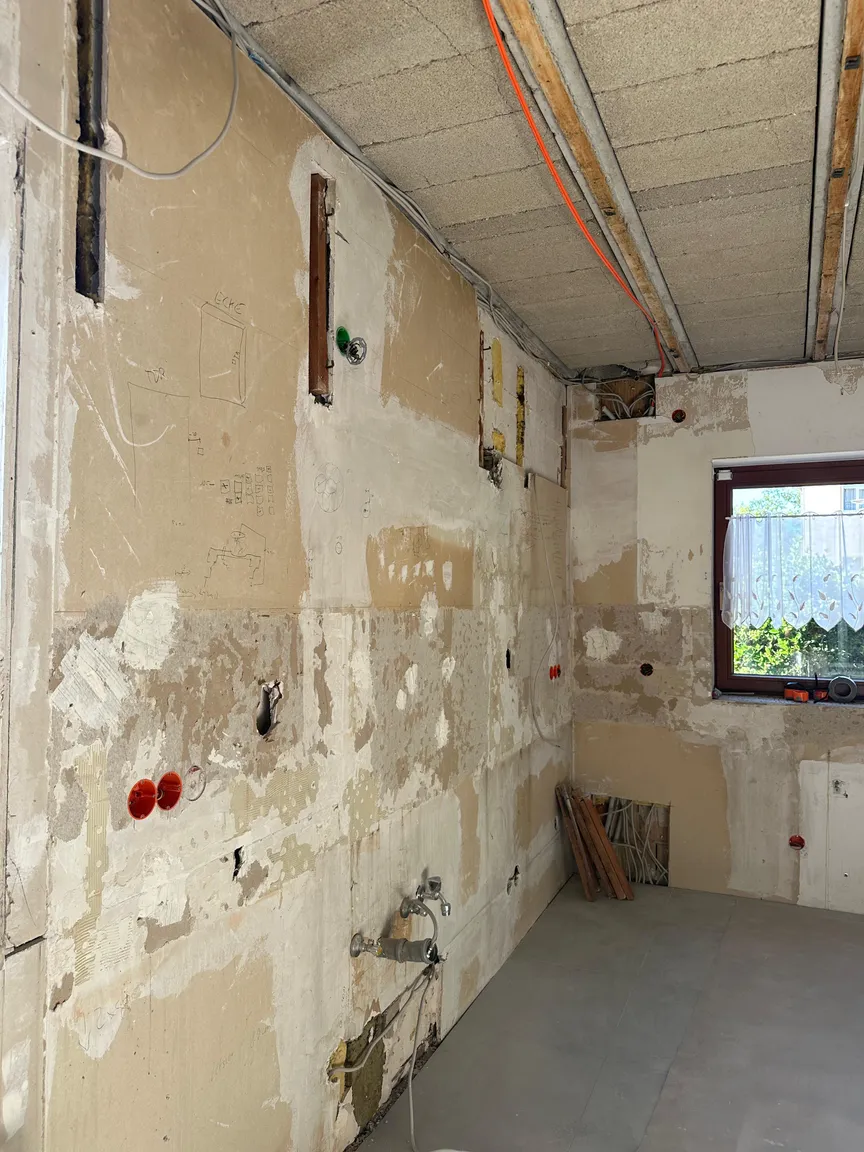 Küchenwand mit freiliegenden Installationsöffnungen und entfernten Wandbelägen