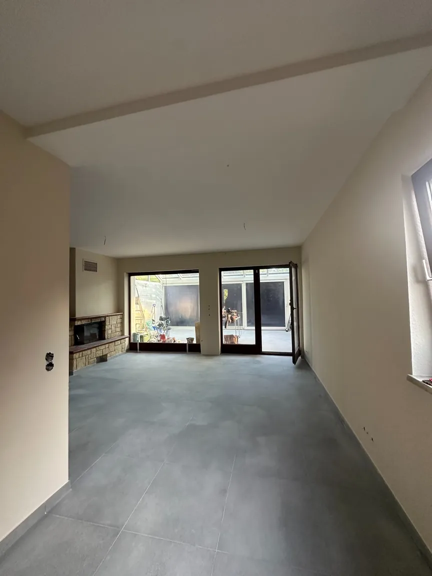 Wohnraum mit geschlossener Decke, hellen Wänden und Blick zum Wintergarten