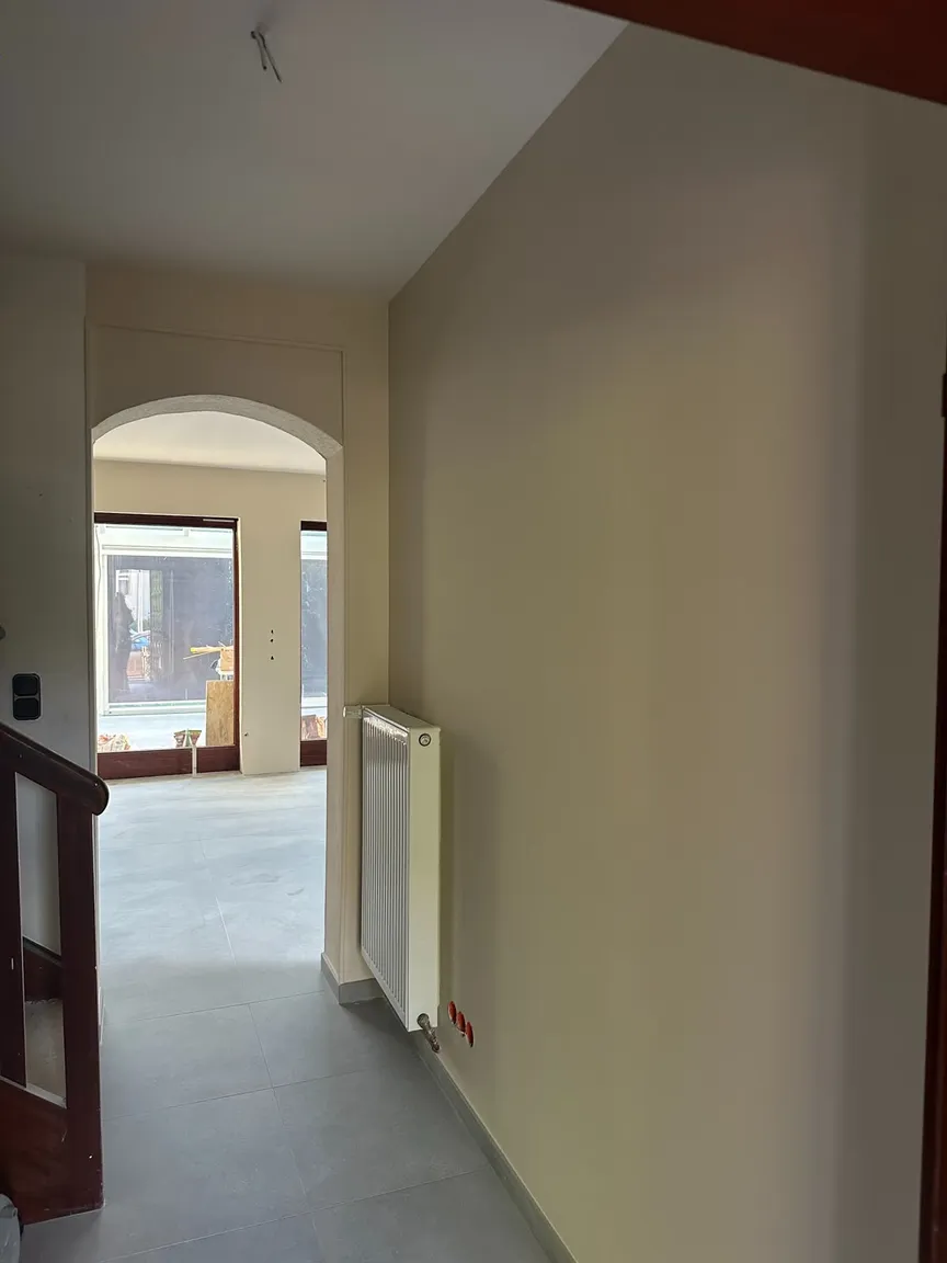 Flur mit gestrichenen Wänden, geschlossener Decke und Durchgang zum Wohnraum